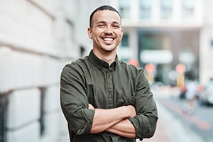 Man in button-up shirt smiling with arms folded