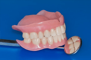 Dentist with blue gloves holding implant dentures
