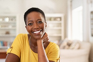 Woman in yellow shirt smiling while relaxing at home