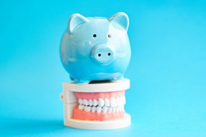 light blue piggy bank sitting on top of a set of dentures in Palm Bay 