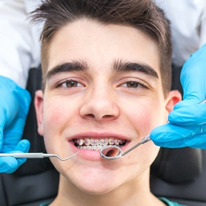 A teenage boy wearing braces in Palm Bay while a dentist performs an examination