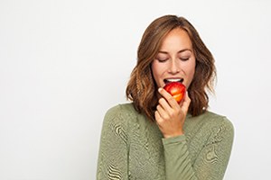 Woman with dental implants in Palm Bay eating an apple