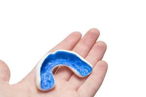 person holding a blue mouthguard in their hands