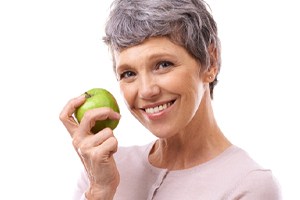 smiling senior woman holding green apple