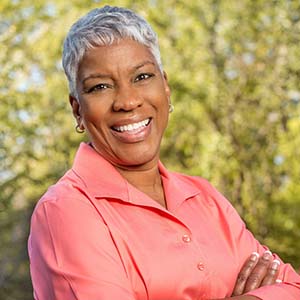 smiling woman with dental implants in Palm Bay standing among trees