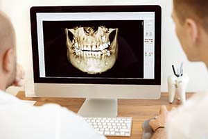 dentists looking at a model of a patient’s jaw on a computer screen
