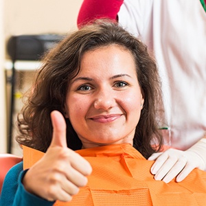 Woman in dental chair giving thumbs up