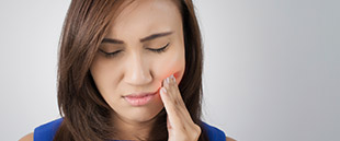Anguished lady holding her cheek in pain before emergency dentistry visit