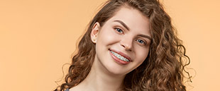 Lady with traditional braces tilting her head smiling