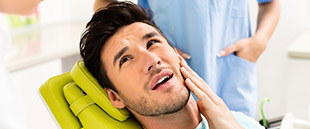 Man in need of T M J therapy holding cheek in pain