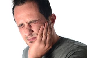 Man in pain holding jaw before T M J therapy