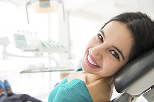 Woman smiling in dental chair after cavity detection screening