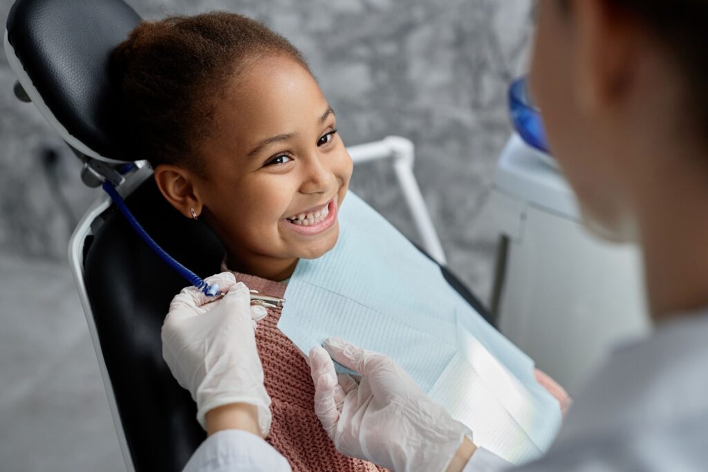 Little girl in dental chair smiling at dentist